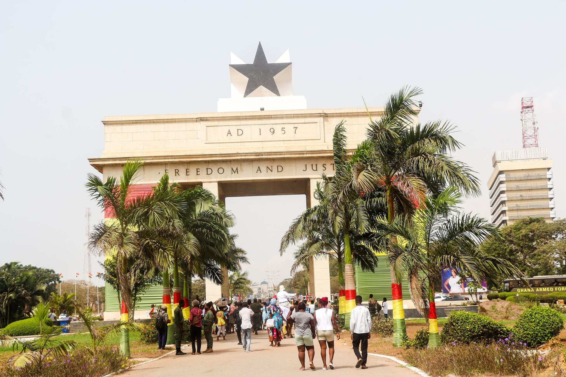 De Onafhankelijkheidsboog met de zwarte ster aan het Black Star Square in Accra, omringd door palmbomen en bezoekers