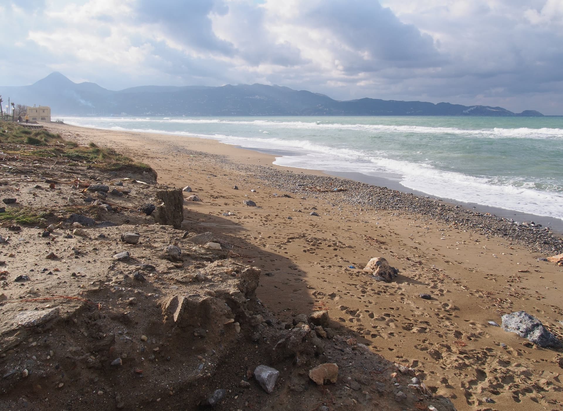 Het lange zandstrand van Ammoudara ten westen van Heraklion, met branding en de bergen van Kreta aan de horizon