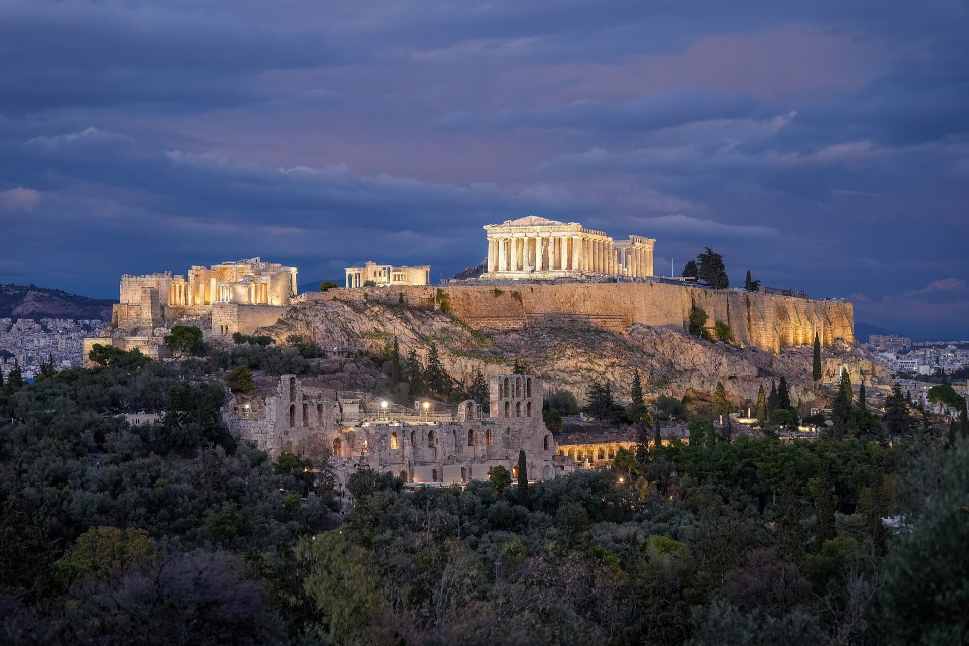 De verlichte Akropolis met het Parthenon boven Athene tijdens het blauwe uur, met het Odeion van Herodes Atticus op de helling