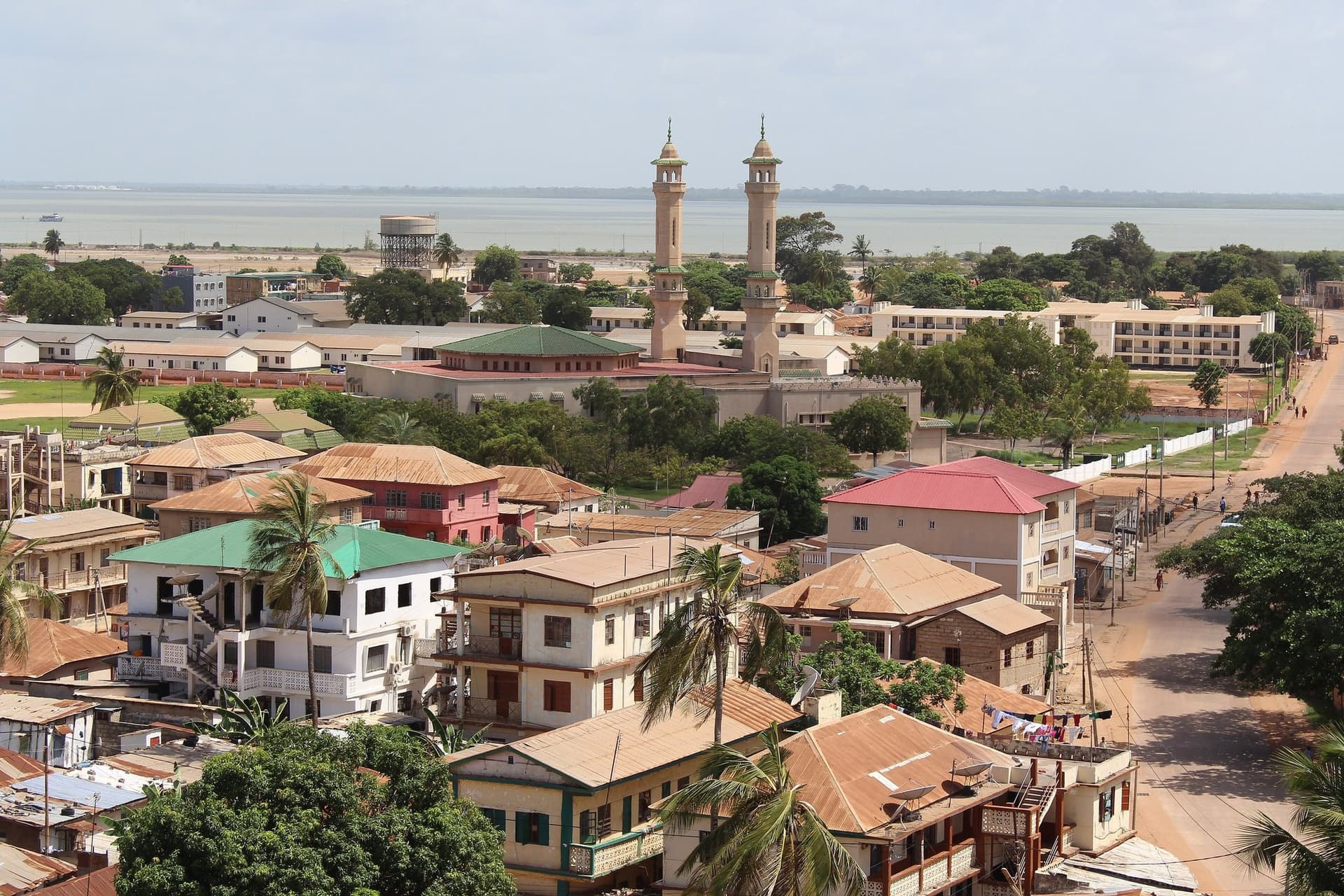 Uitzicht over de daken van Banjul met een moskee met twee minaretten en de monding van de Gambia-rivier op de achtergrond