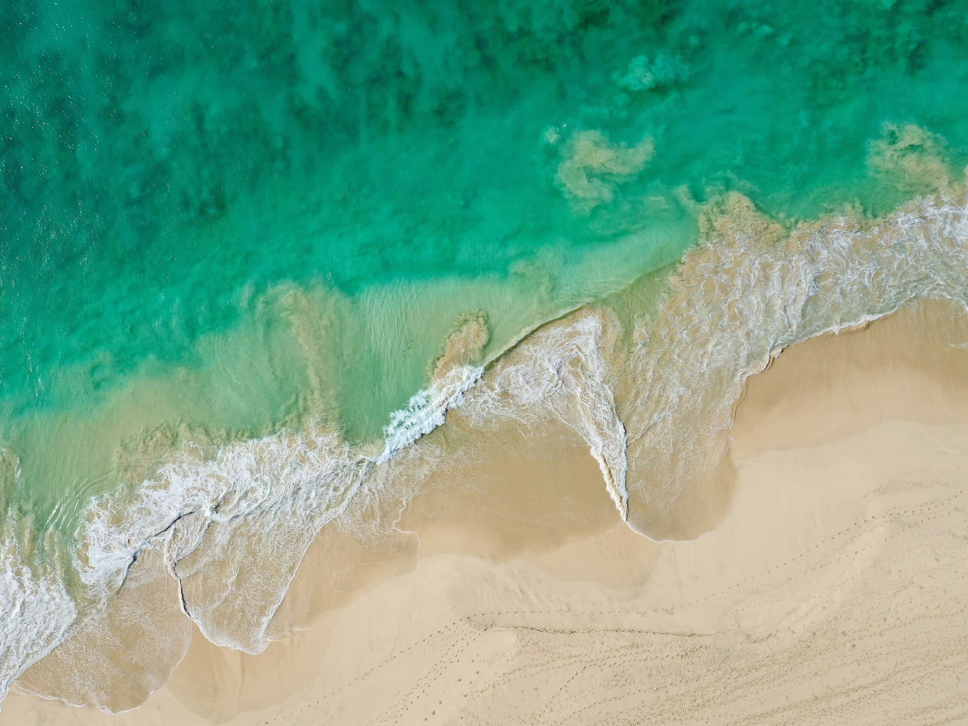 Luchtfoto van een wit zandstrand op Boa Vista waar turquoise golven van de Atlantische Oceaan op het strand rollen