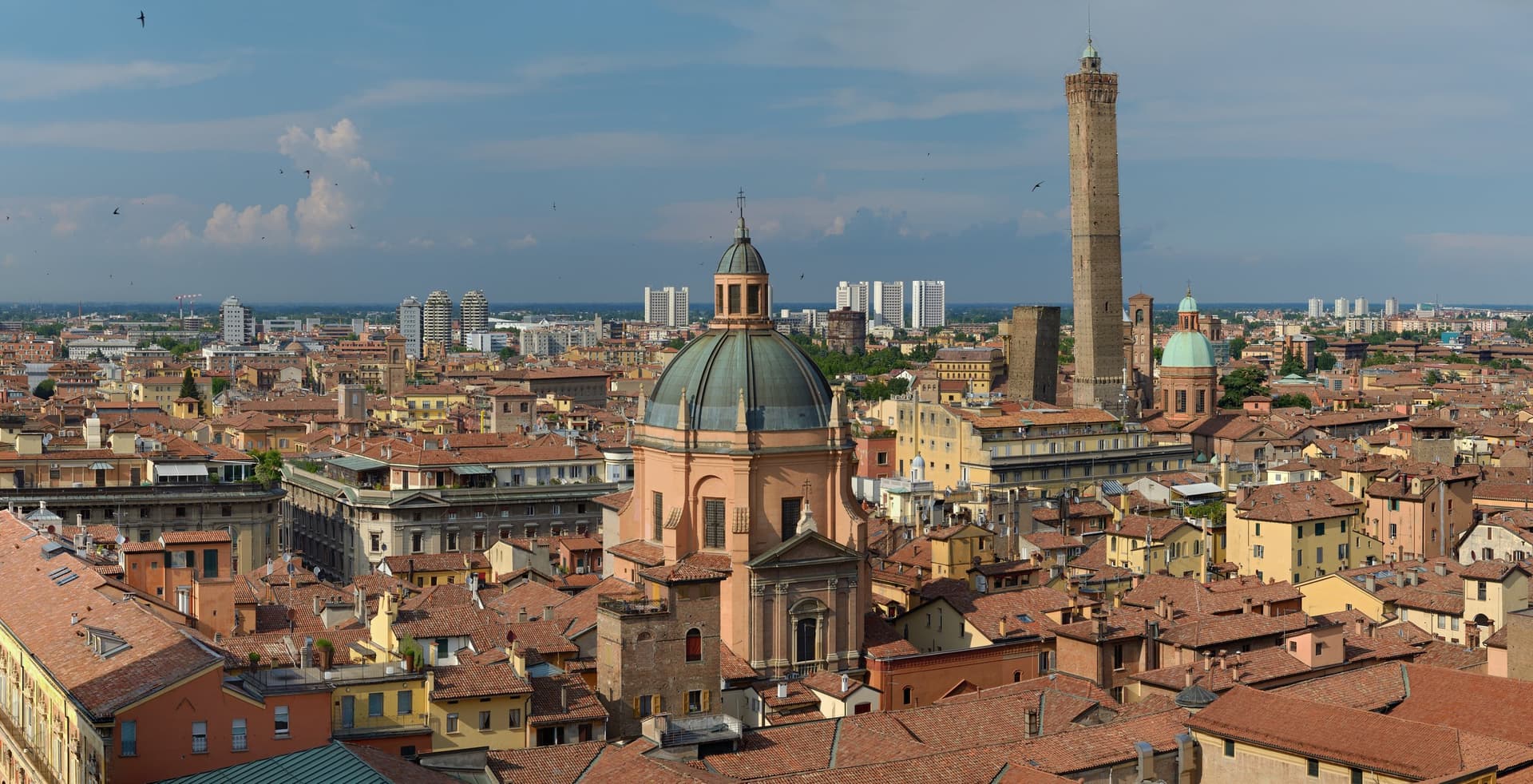 Panorama over de rode daken van Bologna met een barokke koepel en de hoge Torre degli Asinelli