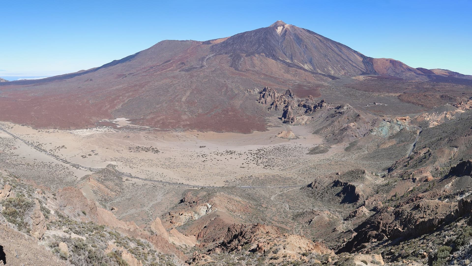 De vulkaan Teide op Tenerife boven de kale lavavlakte van Las Cañadas onder een strakblauwe lucht
