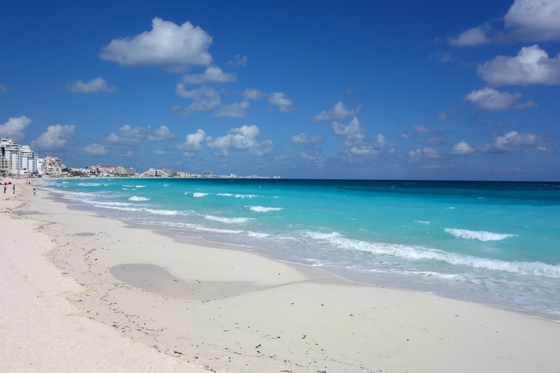 Wit zandstrand en turquoise Caribische zee in de Zona Hotelera van Cancún, met hotels aan de horizon links