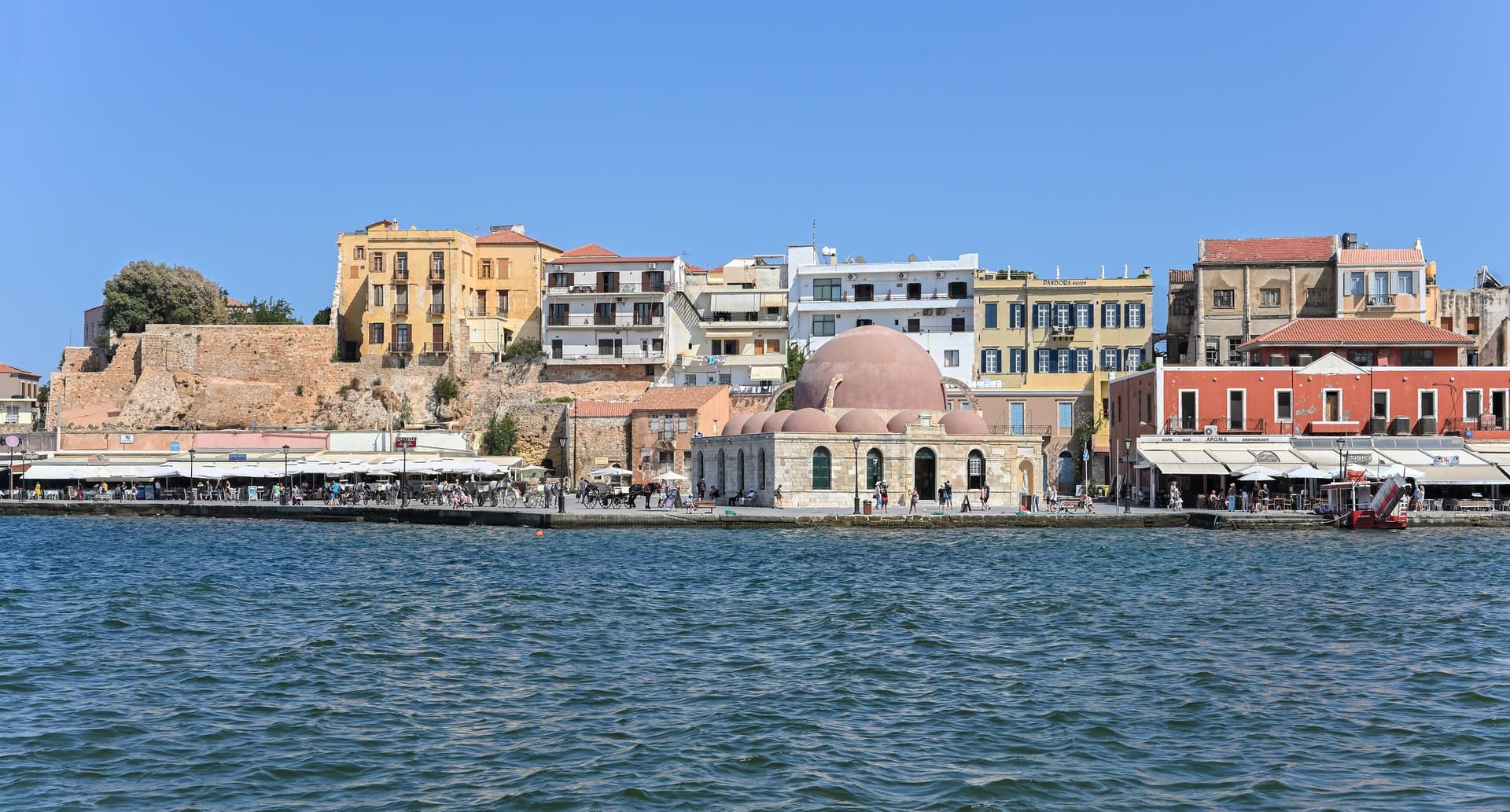 De Venetiaanse haven van Chania met pastelkleurige huizen en de koepels van de Küçük Hasan-moskee aan het water