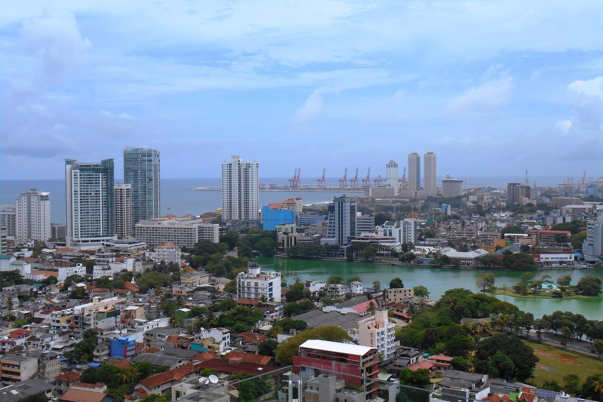 Uitzicht over Colombo met het Beira-meer, groene wijken en de hoge torens aan de kust onder een blauwe lucht met wolken