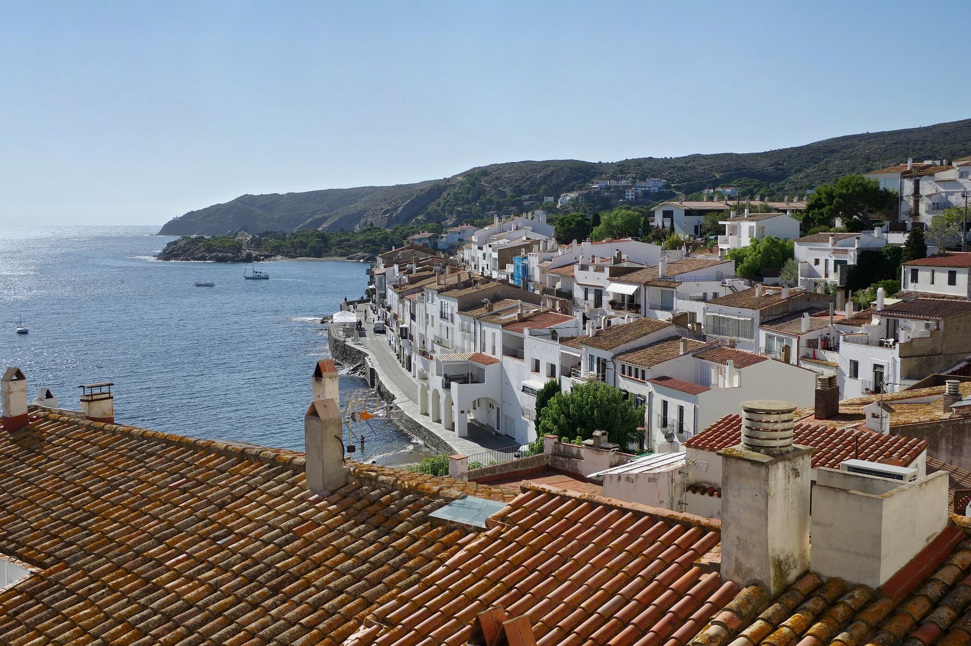 Witte huizen en oranje daken van Cadaqués aan een blauwe baai aan de Costa Brava
