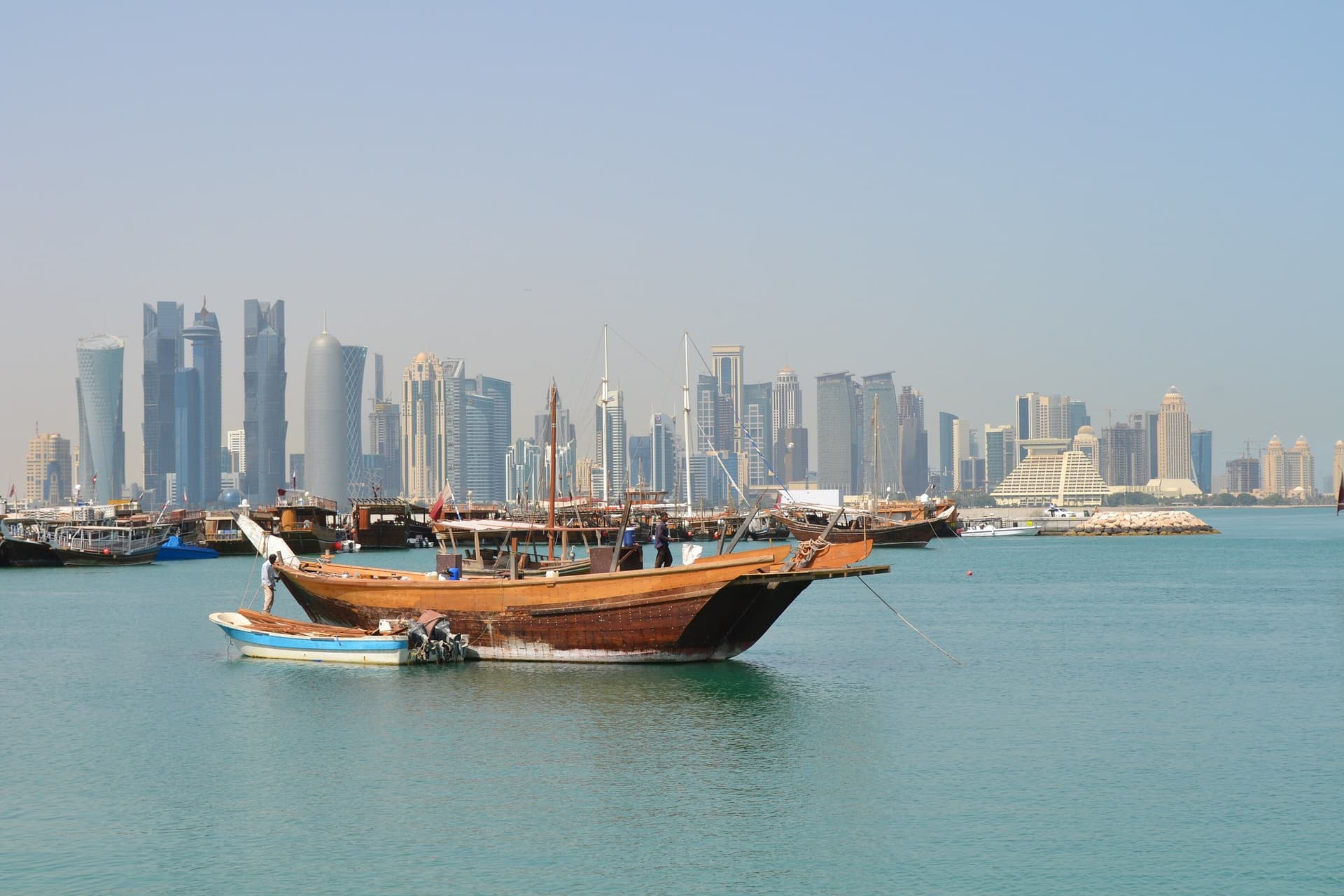 Een houten dhow op het water voor de skyline van West Bay in Doha