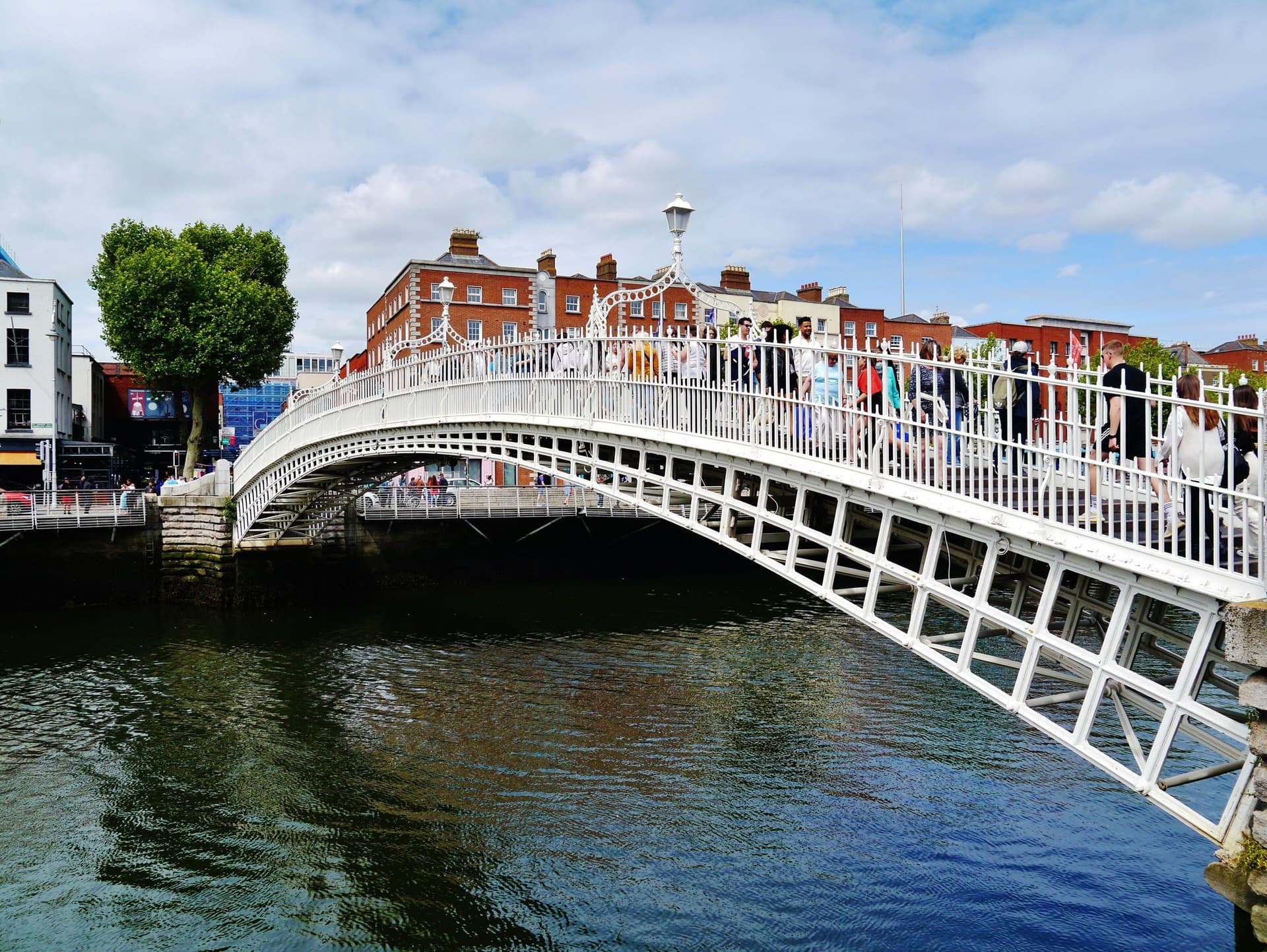 De witte gietijzeren Ha'penny Bridge over de rivier de Liffey in Dublin