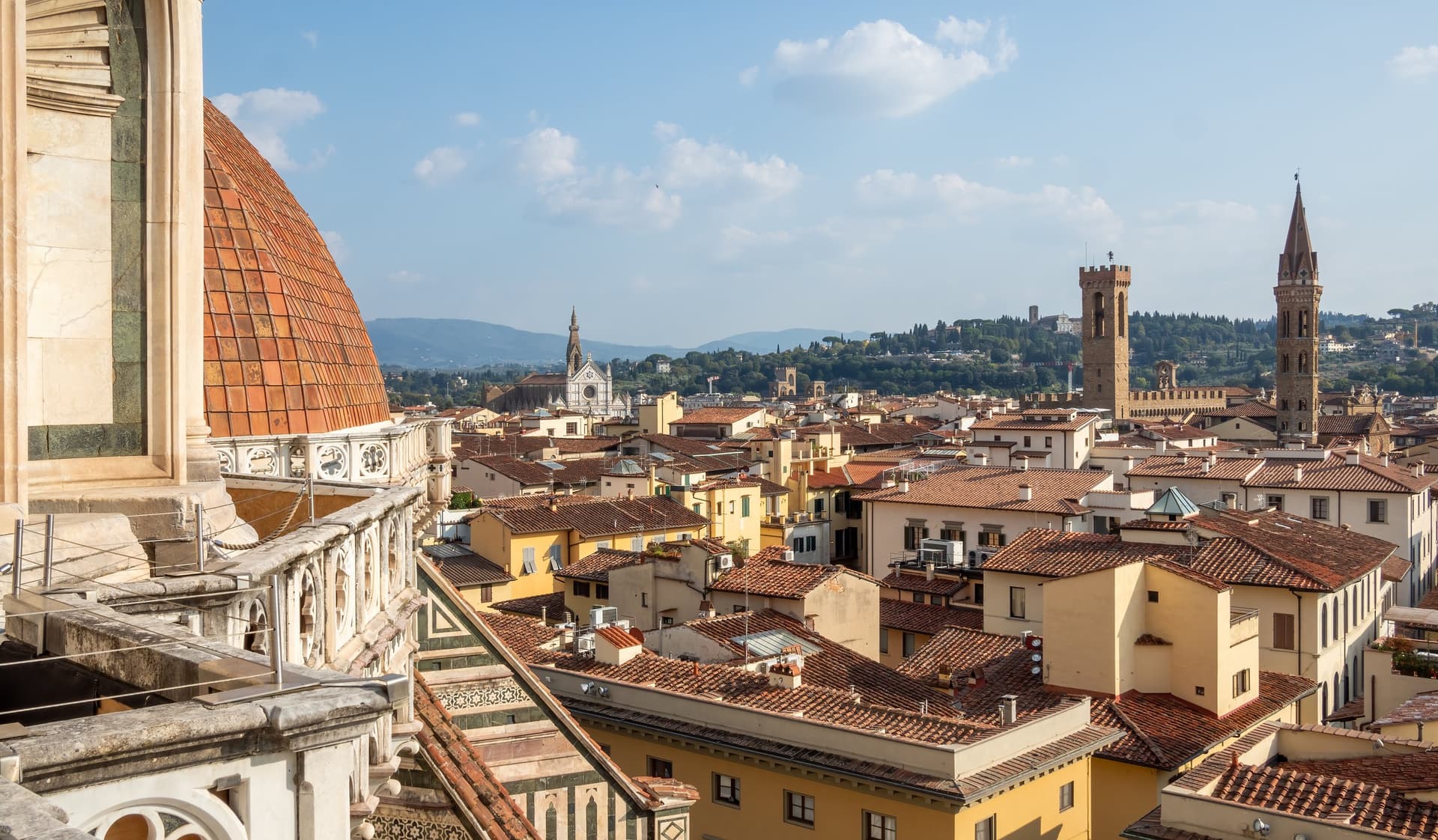 Uitzicht vanaf het dakterras van de Duomo over de rode daken en middeleeuwse torens van Florence, met de heuvels erachter