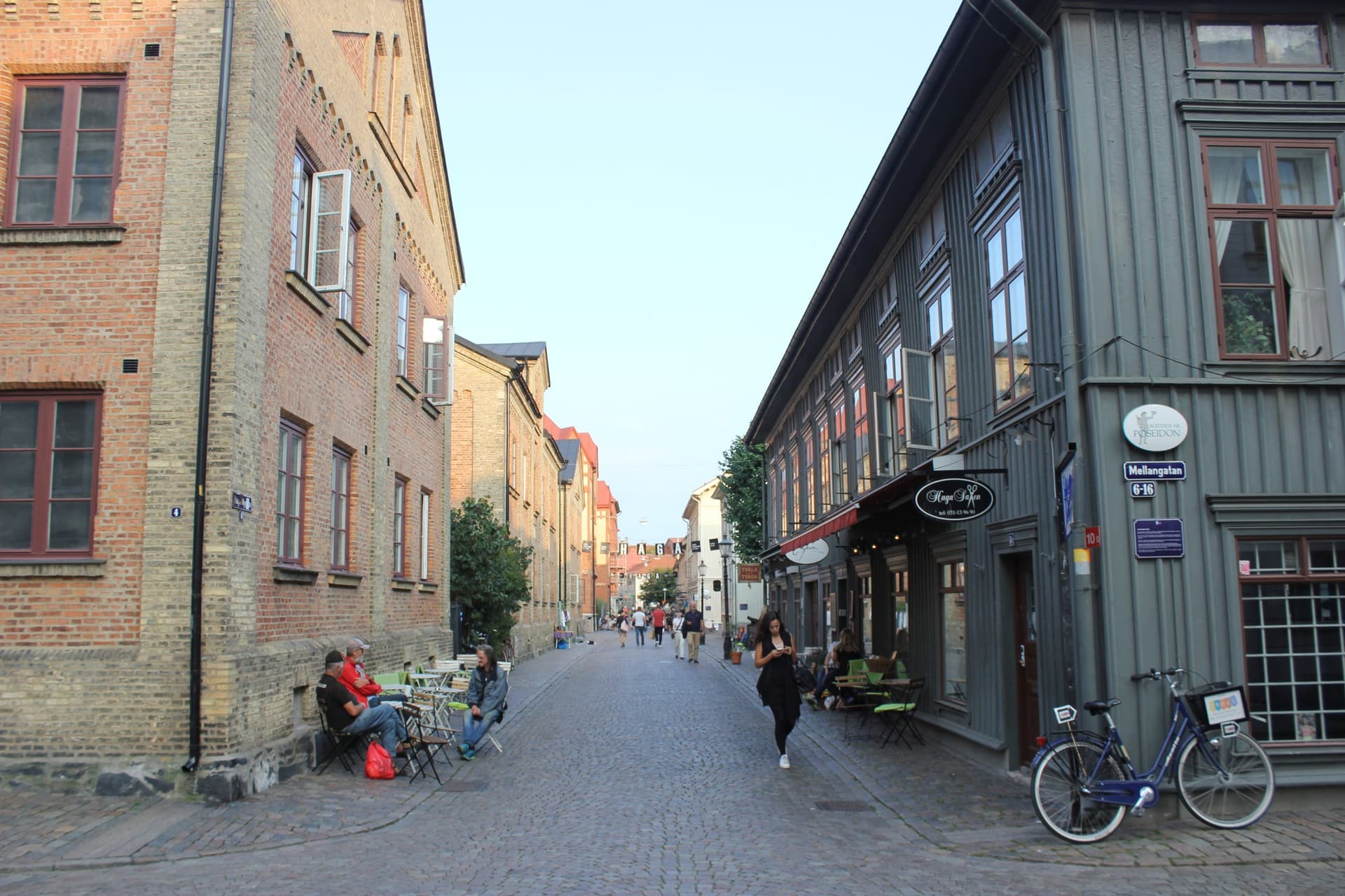 De autovrije straat Haga Nygata in Göteborg met houten en bakstenen huizen, terrasjes en een fiets in de zon