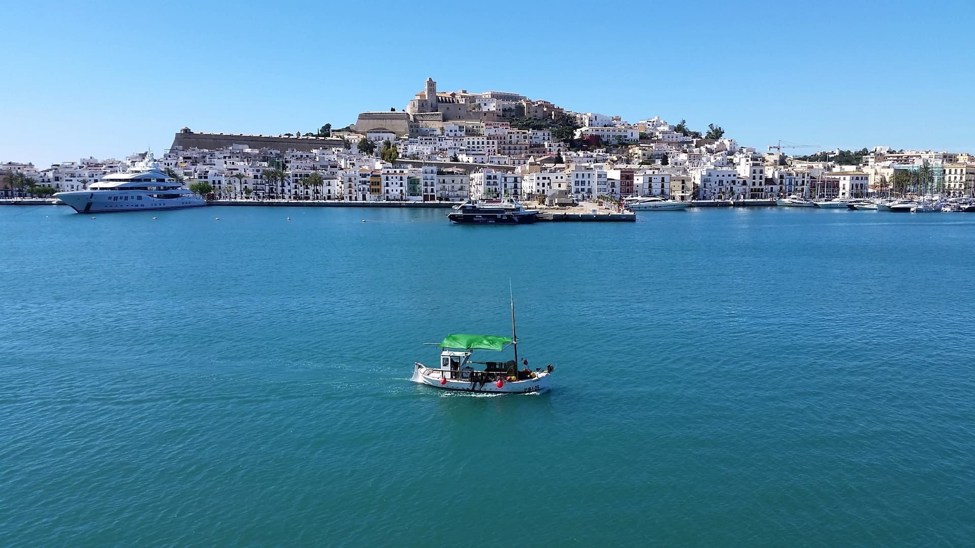 De witte oude stad Dalt Vila op de heuvel boven de haven van Ibiza-stad, met jachten en helderblauw water