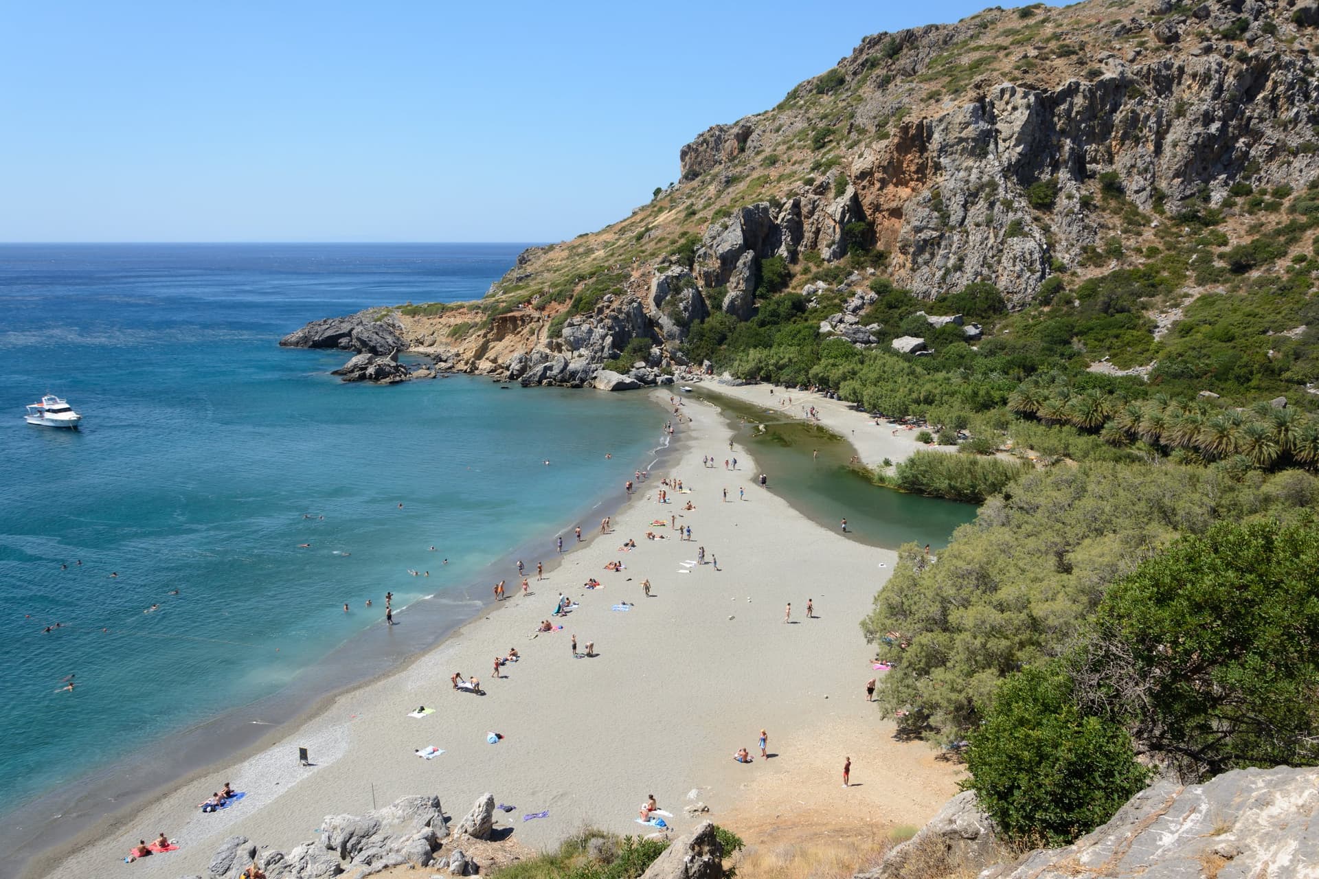 Het palmenstrand van Preveli aan de zuidkust van Kreta, waar de rivier tussen rotsen en palmbomen in de blauwe Libische Zee uitkomt