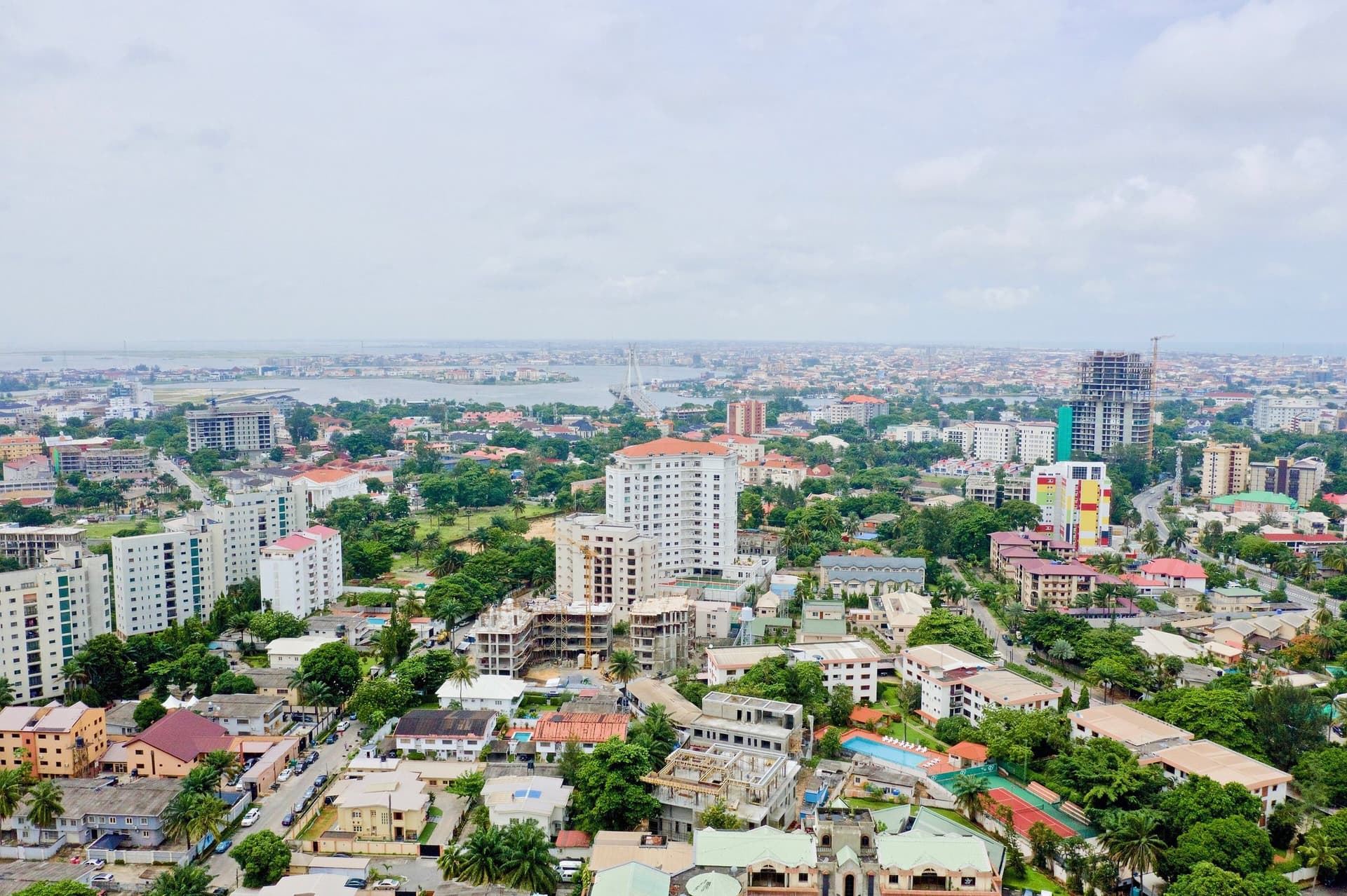 Uitzicht vanaf hoogte over Ikoyi in Lagos, met groene straten, appartementengebouwen en de lagune met Lagos Island in de verte