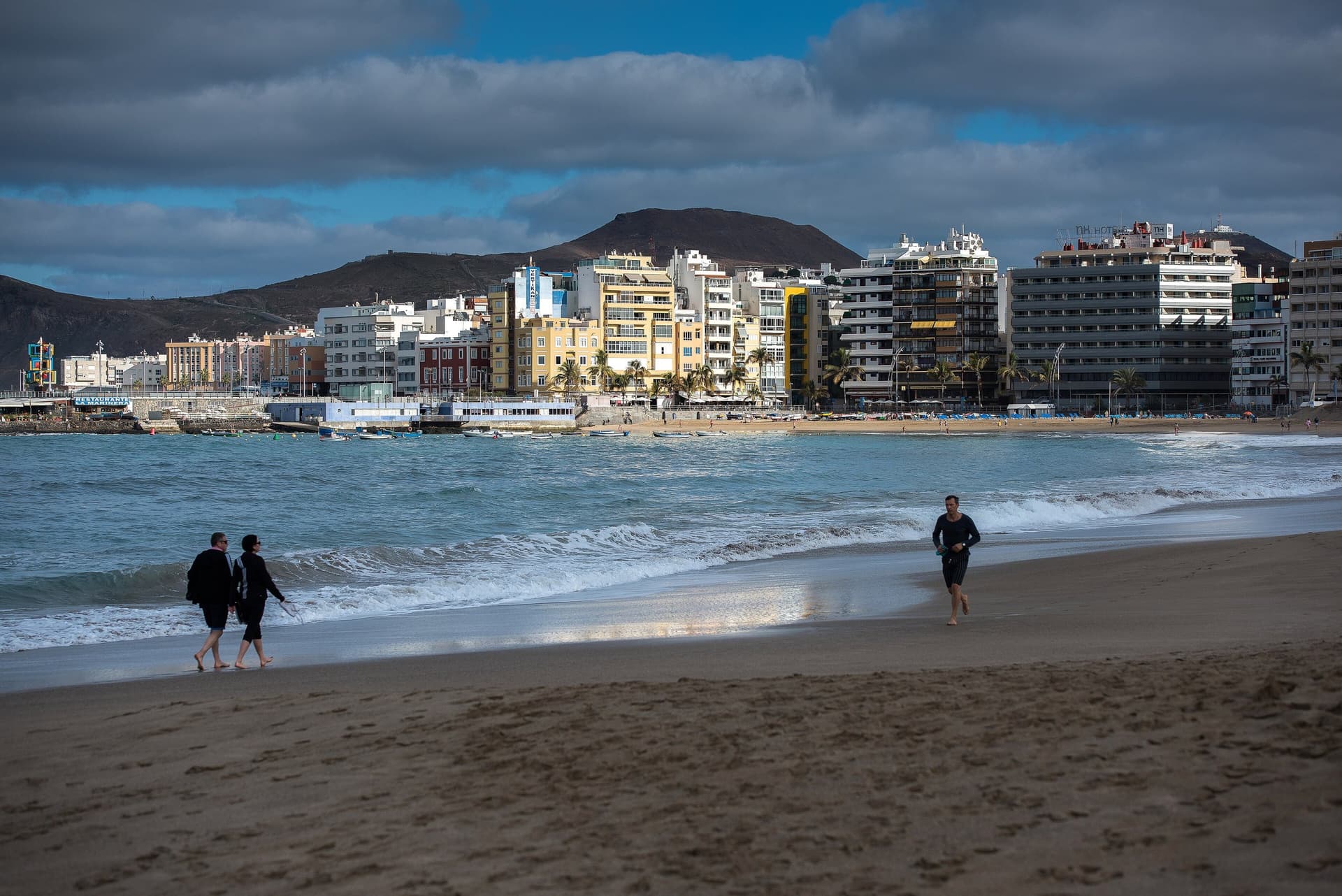 Het stadsstrand Las Canteras in Las Palmas de Gran Canaria met wandelaars in de branding en flatgebouwen aan de boulevard