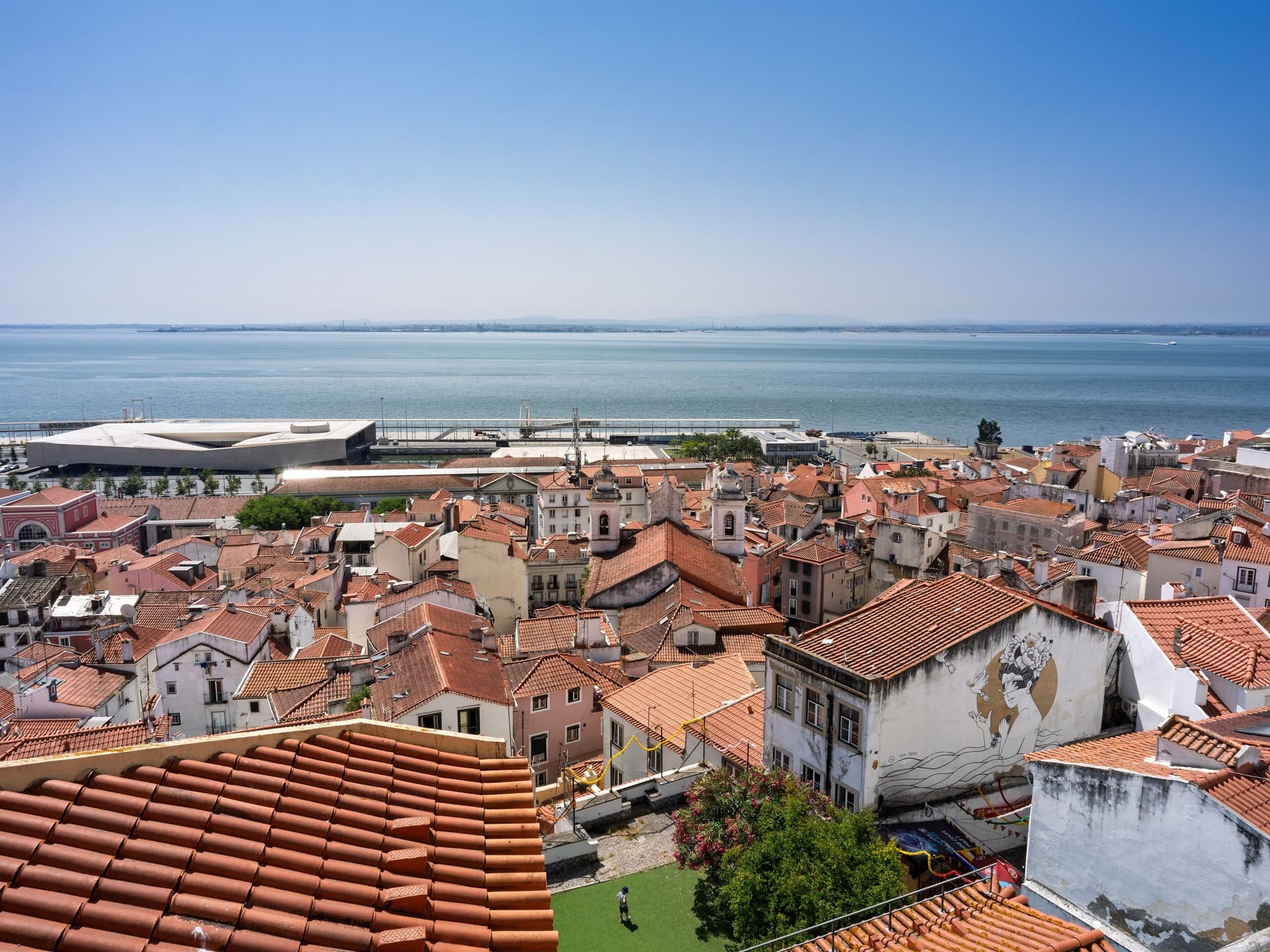 Uitzicht vanaf de Miradouro de Santa Luzia over de oranje daken van Alfama naar de Taag in Lissabon