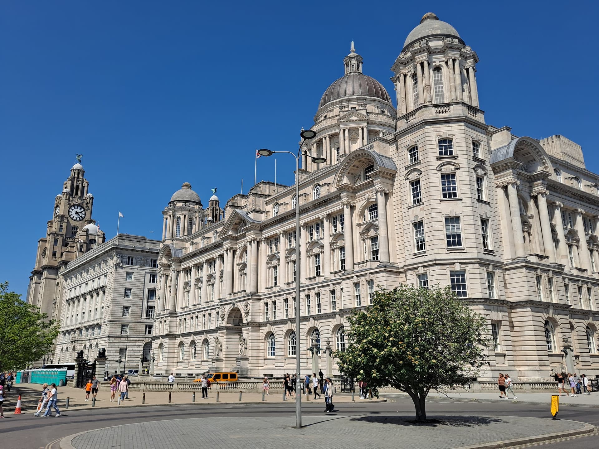 De Three Graces aan Pier Head in Liverpool, met het Royal Liver Building en het Port of Liverpool Building in de zon