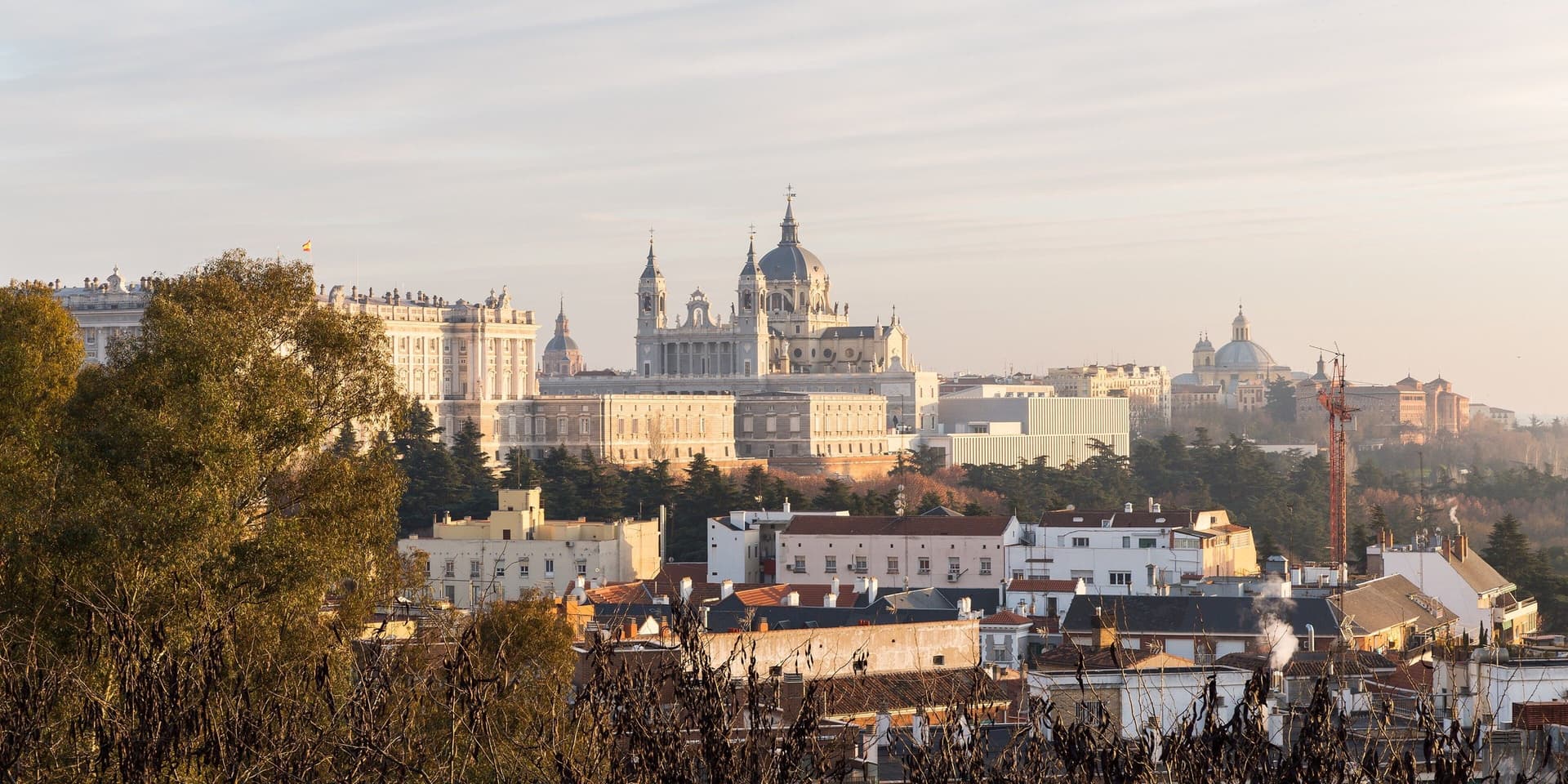 De kathedraal van de Almudena en het Koninklijk Paleis boven de daken van Madrid in warm avondlicht