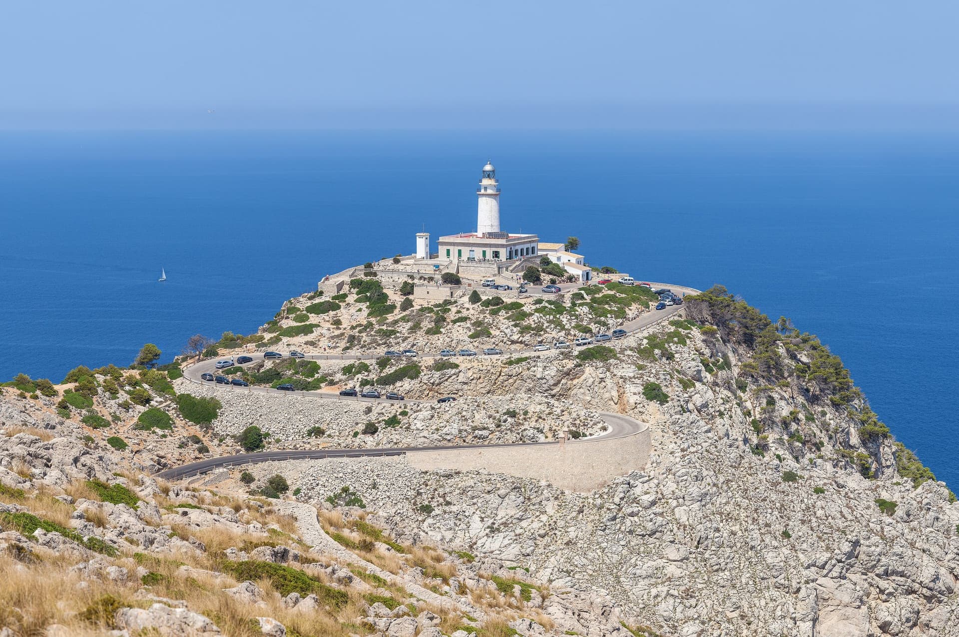 De vuurtoren van Cap de Formentor op een rotsige landtong in het noorden van Mallorca, met de kronkelende weg erheen en een diepblauwe zee