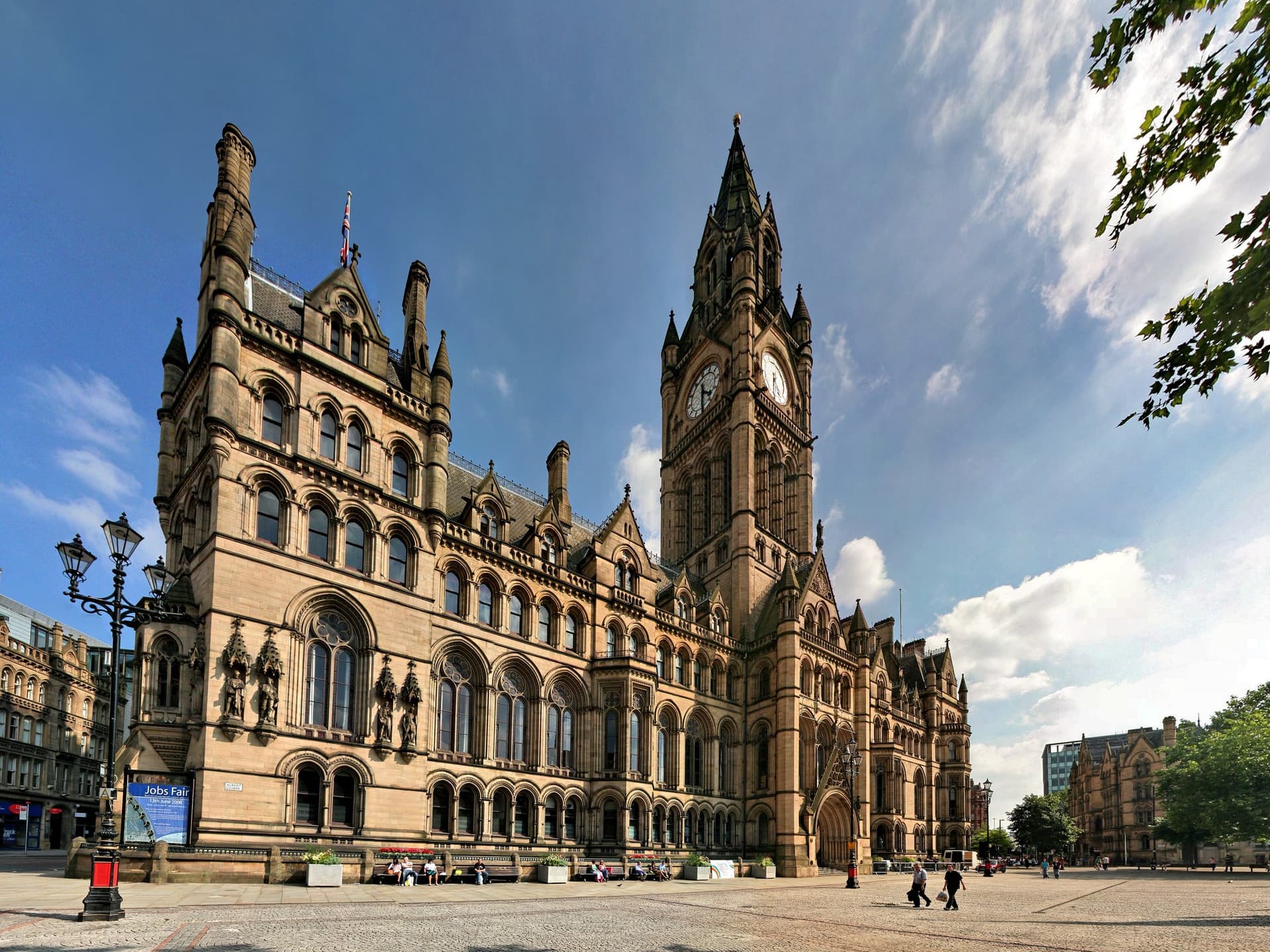 De neogotische Manchester Town Hall met klokkentoren aan Albert Square onder een blauwe lucht