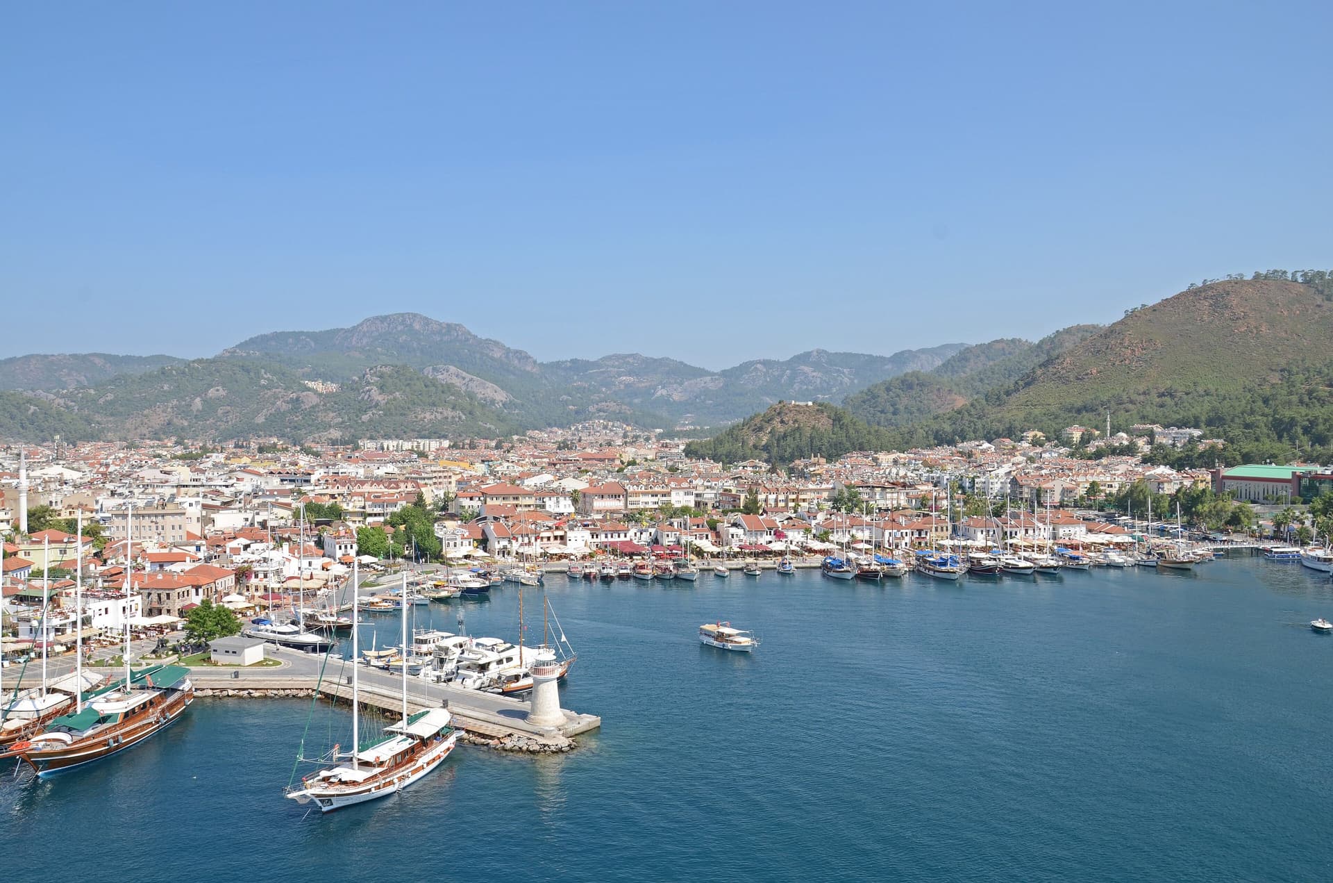 Uitzicht over de haven en de jachthaven van Marmaris, met witte huizen tegen de beboste bergen rond de baai