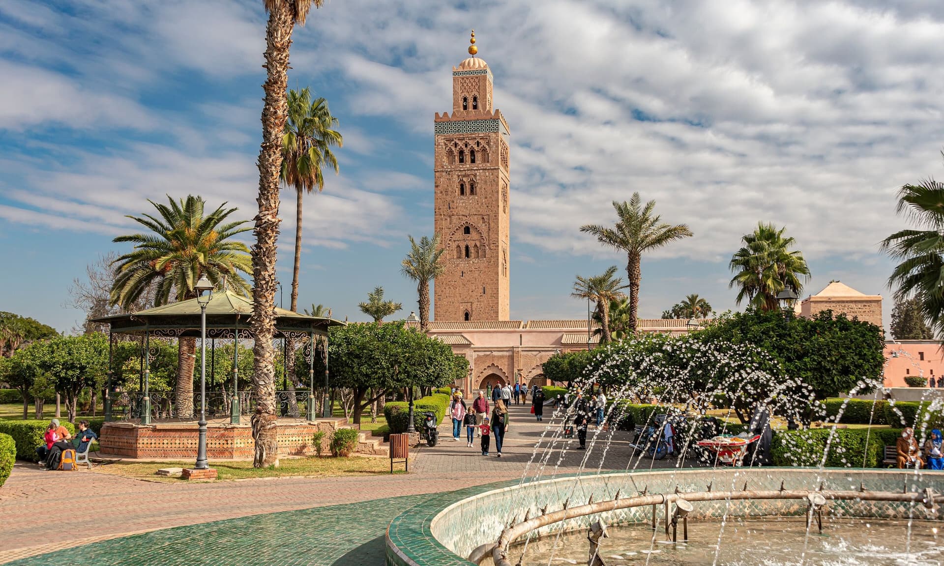 De minaret van de Koutoubia-moskee in Marrakech met palmbomen en fonteinen op de voorgrond