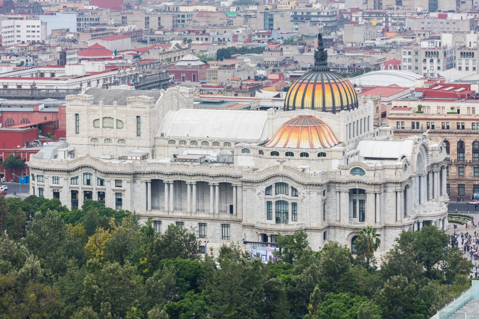 Het witmarmeren Palacio de Bellas Artes met zijn oranje-gele koepels, van bovenaf gezien boven de bomen van de Alameda Central in Mexico-Stad