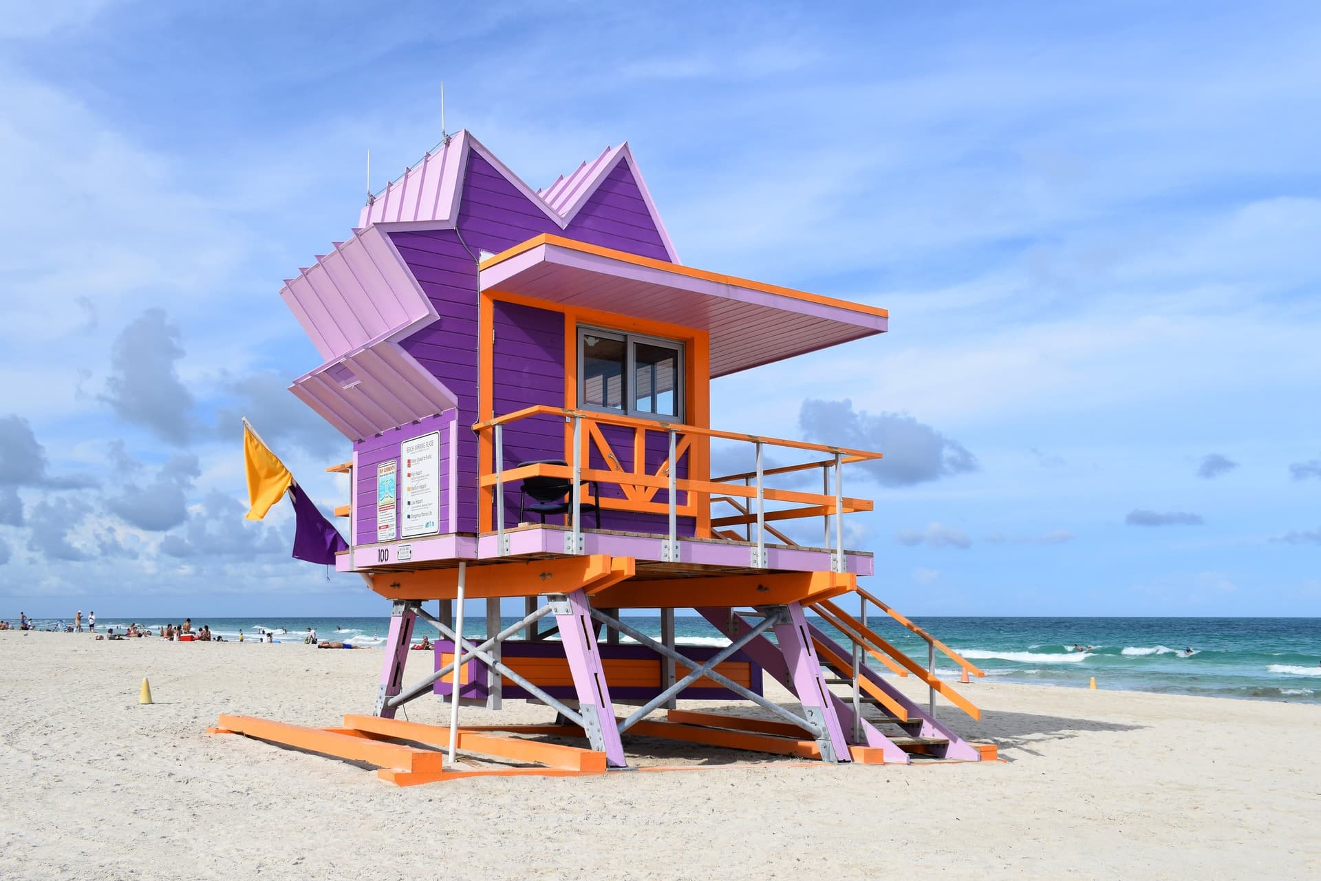 Paars-oranje strandwachtershuisje in art-decostijl op het witte strand van South Beach, met de turquoise Atlantische Oceaan erachter