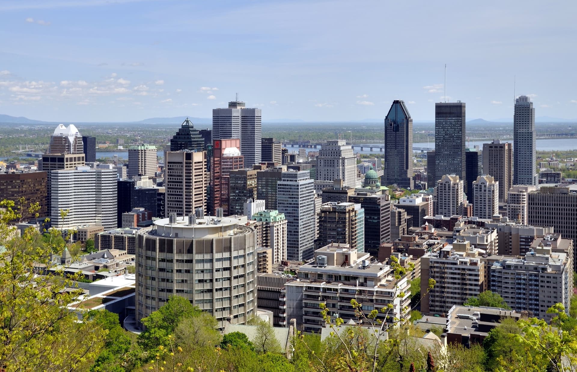 Uitzicht vanaf de Mont Royal over de wolkenkrabbers van downtown Montréal met de Saint-Laurent op de achtergrond, op een zonnige lentedag
