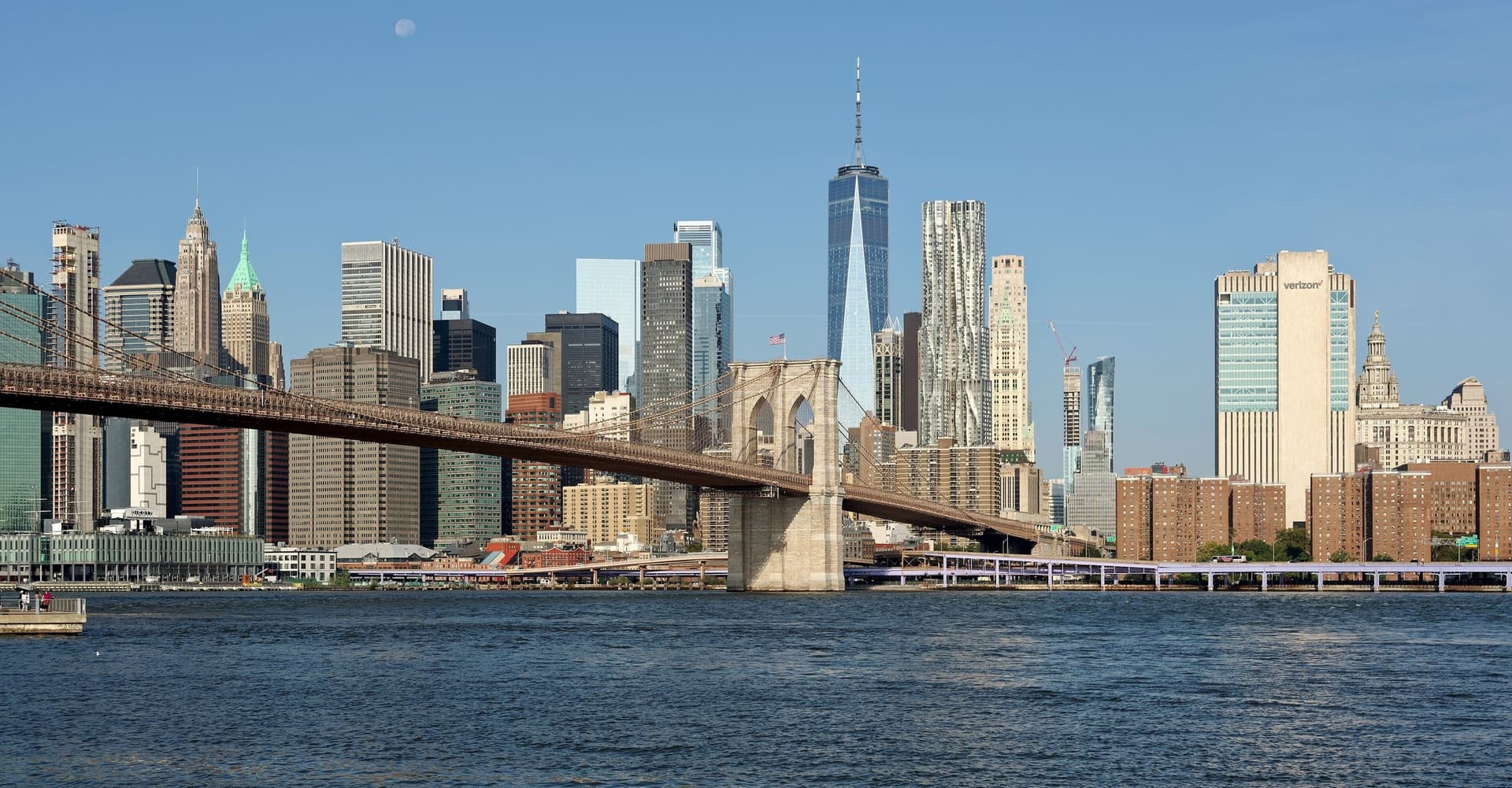 De skyline van Lower Manhattan met One World Trade Center en de Brooklyn Bridge op een zonnige dag