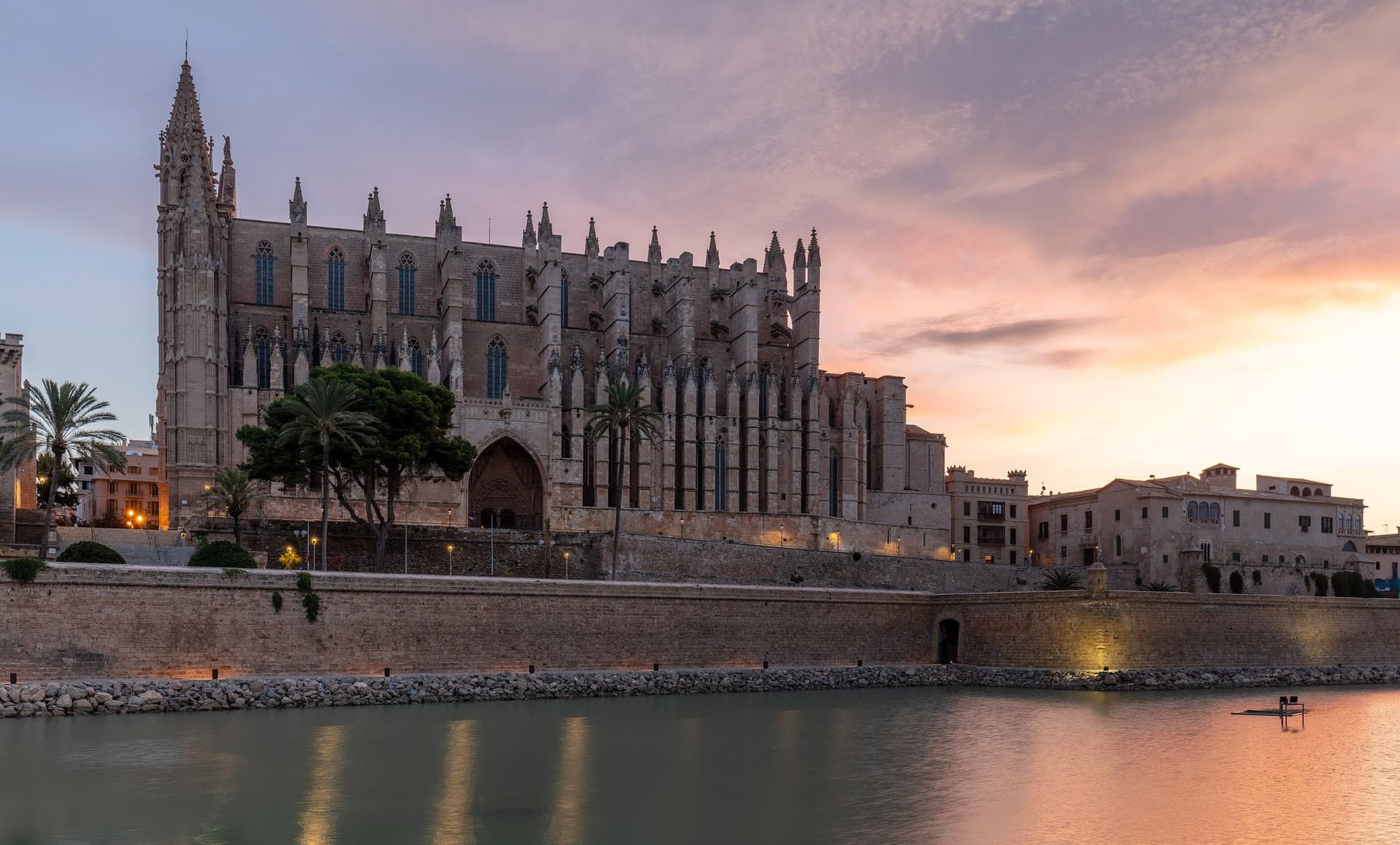 De gotische kathedraal La Seu van Palma de Mallorca boven de oude stadsmuur, weerspiegeld in het water bij zonsondergang