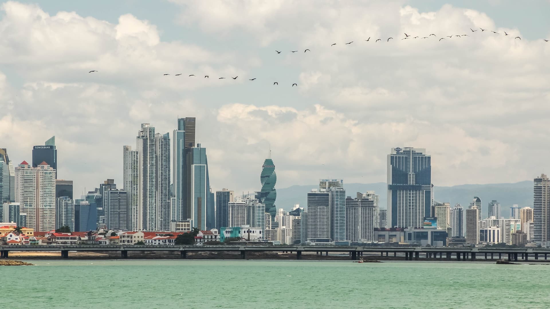 De skyline van Panama-Stad met glazen torens en de gedraaide F&F Tower boven de baai, gezien over het water vanaf de Cinta Costera
