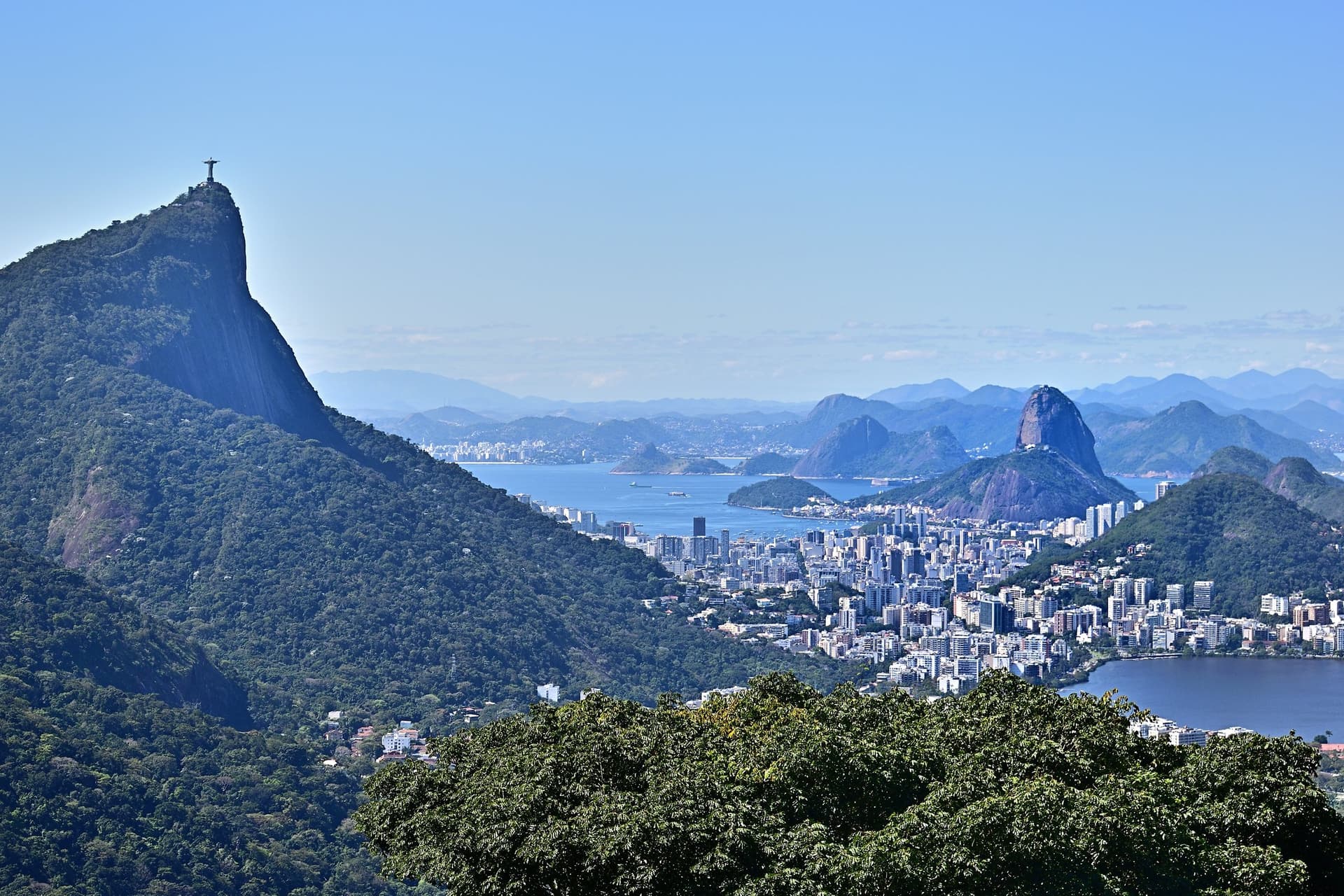 De Corcovado met het Cristo Redentor-beeld boven de Lagoa en de wijken van Rio de Janeiro, met de Suikerbroodberg in de baai op de achtergrond