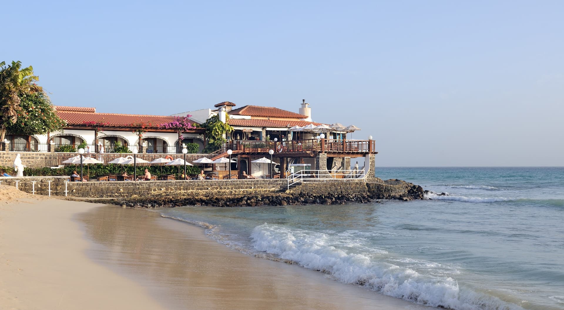 Het strand van Santa Maria op Sal met een restaurant met terras direct aan het water, rustige golven en een heldere blauwe lucht