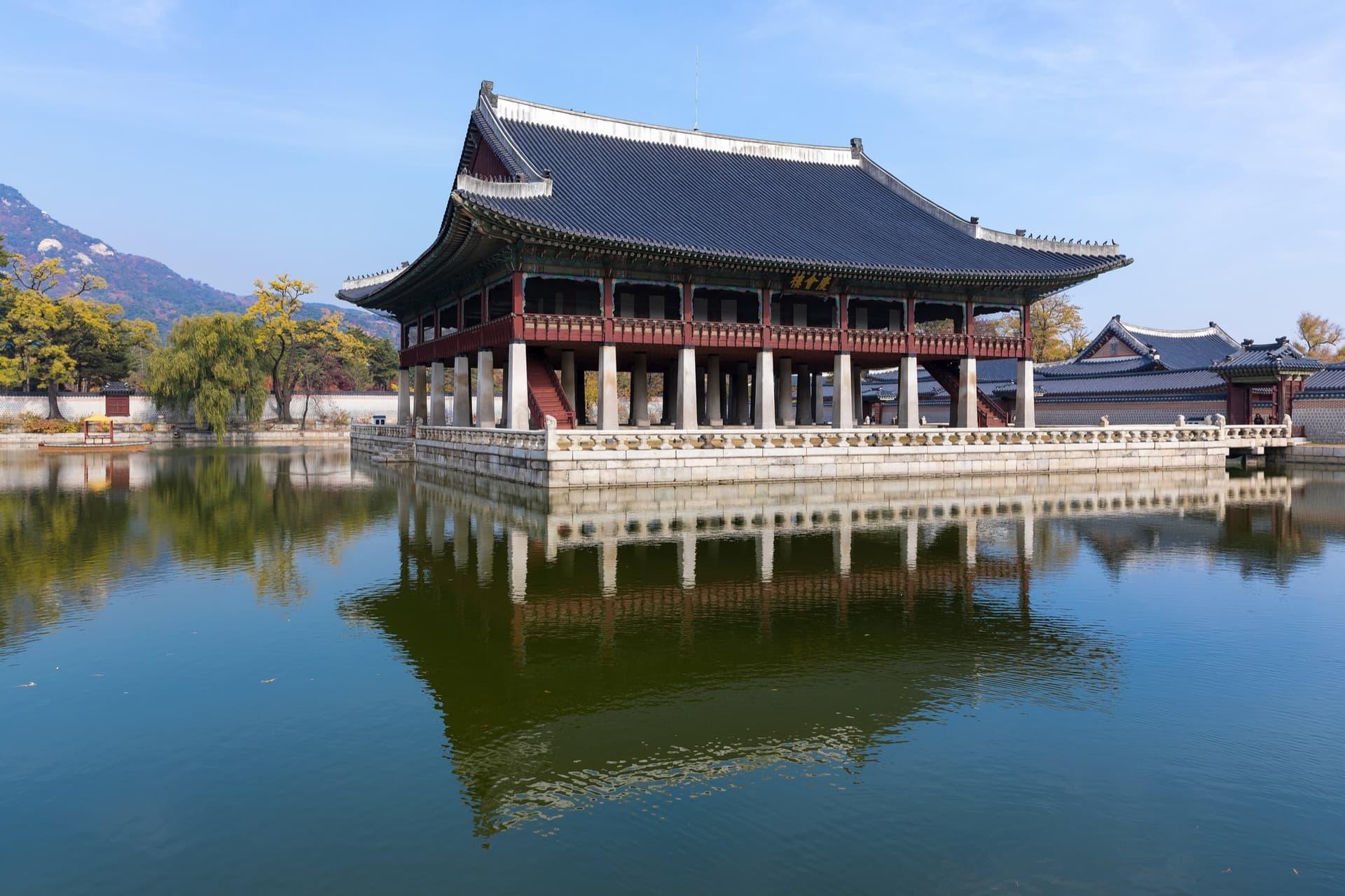 Het Gyeonghoeru-paviljoen van het Gyeongbokgung-paleis in Seoul, gespiegeld in de vijver onder een blauwe herfstlucht