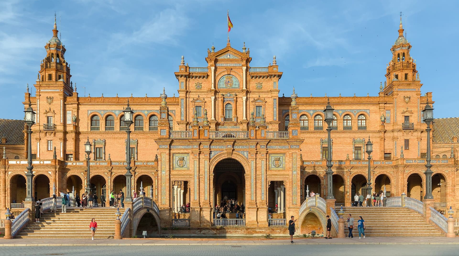 Het halfronde paleis van de Plaza de España in Sevilla met torens, arcaden en tegelwerk onder een blauwe lucht