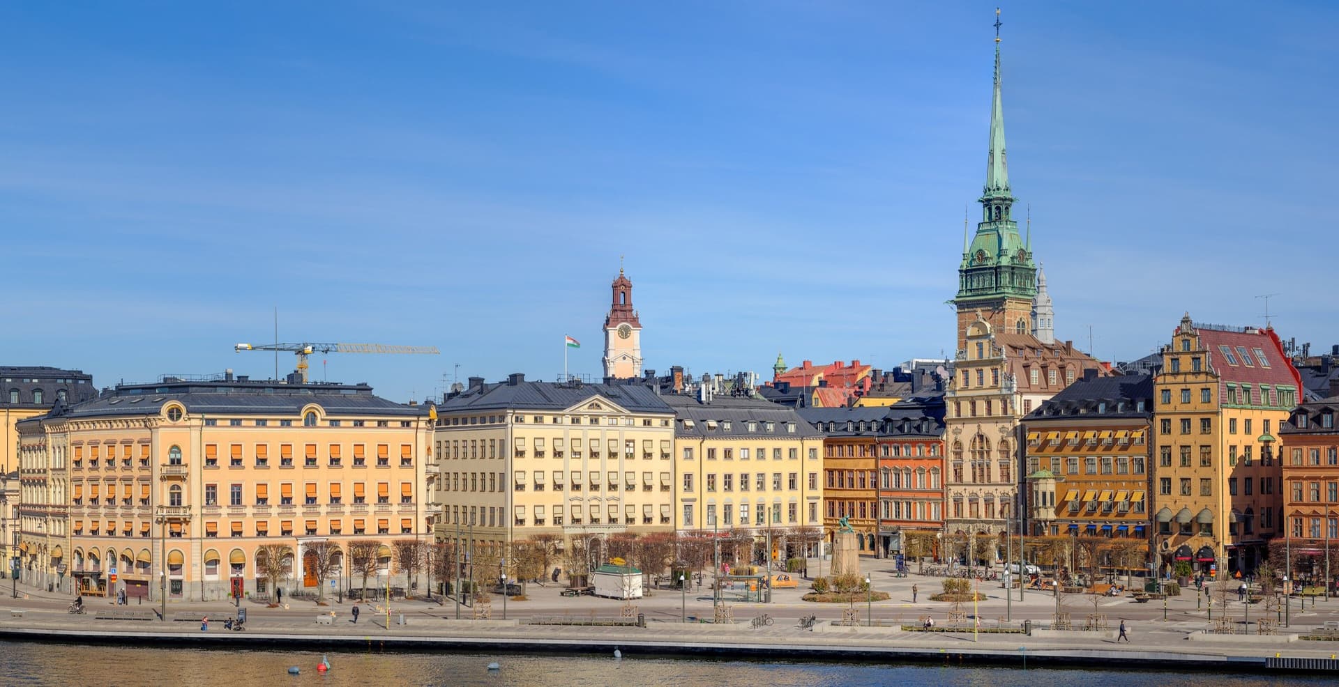 Kleurrijke gevels van Gamla stan aan het water bij Kornhamnstorg in Stockholm, met de groene torenspits van de Duitse kerk