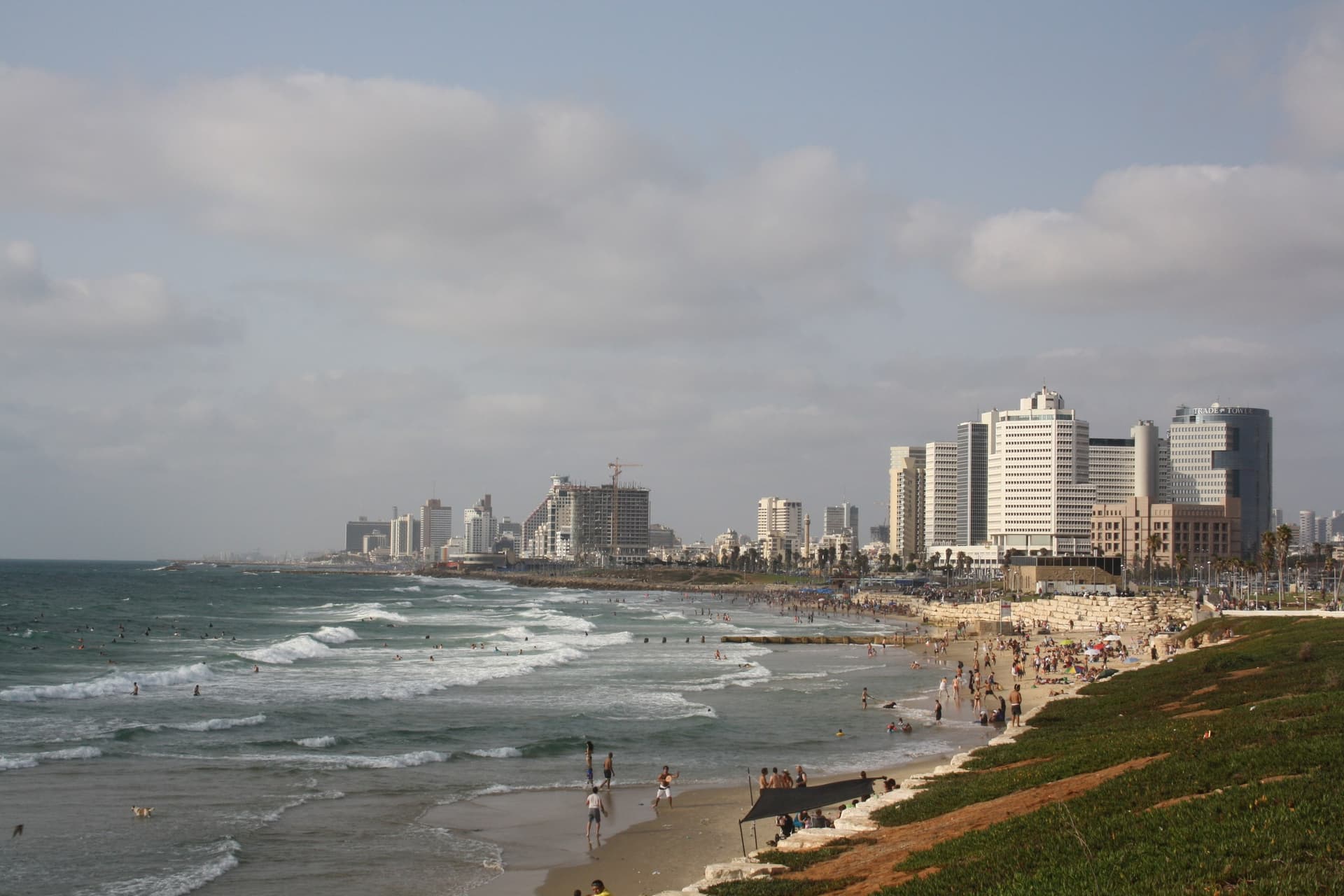 Het stadsstrand van Tel Aviv met branding, zonnebaders en de hotels en torens langs de boulevard