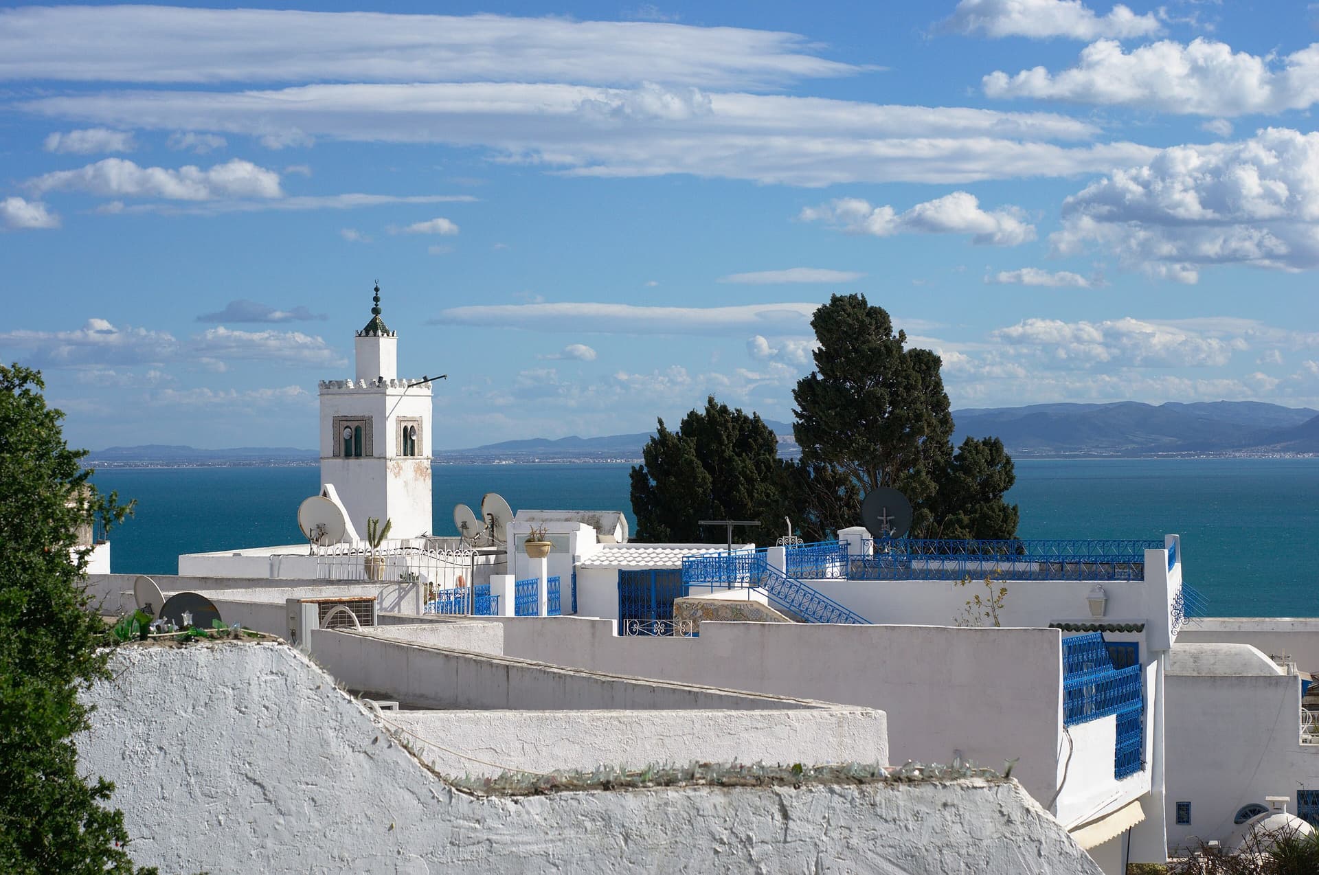 Witte huizen met blauwe accenten en een minaret in Sidi Bou Saïd bij Tunis, met zee op de achtergrond