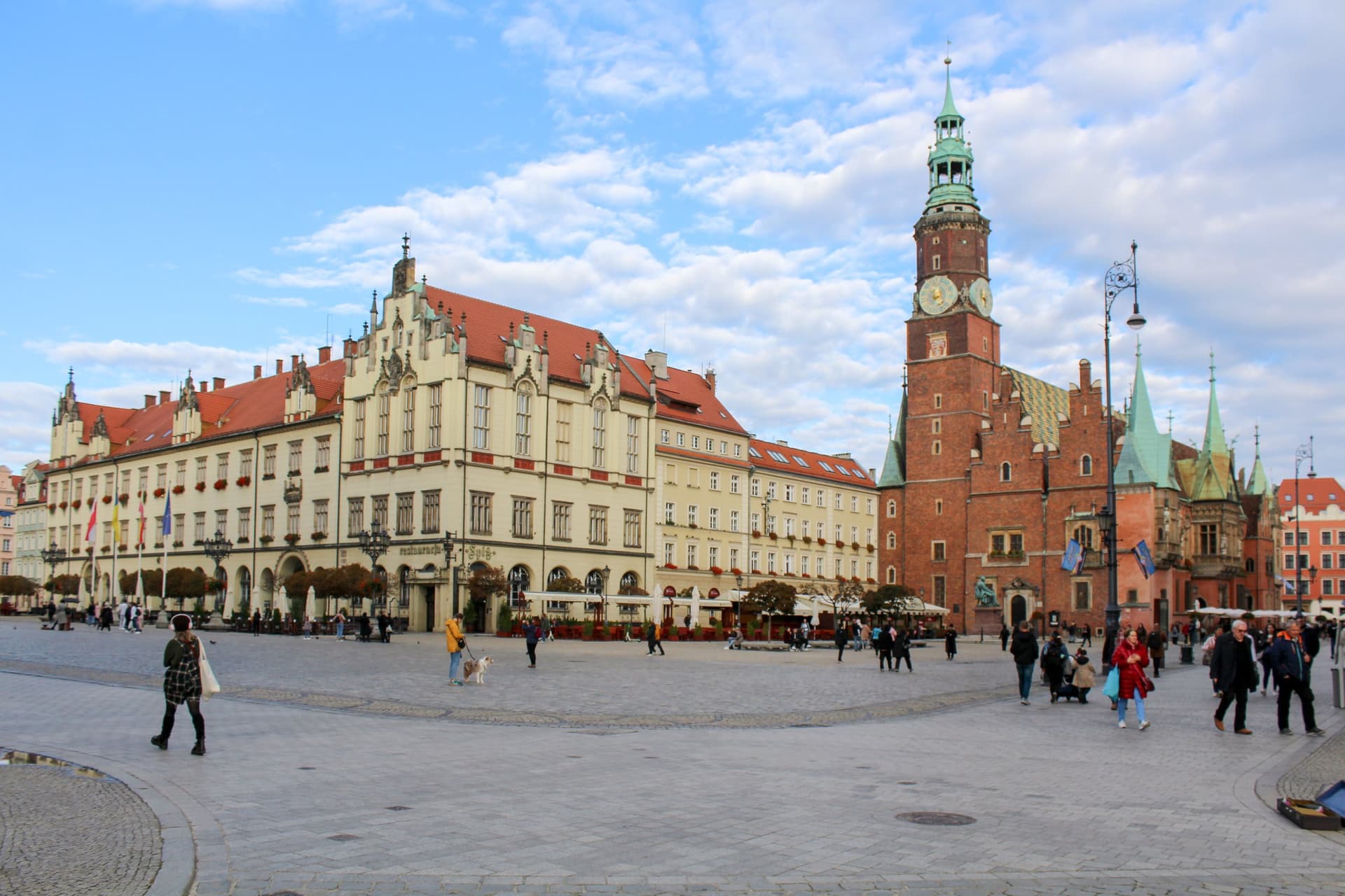 Het gotische oude stadhuis en het nieuwe stadhuis aan het Rynek in Wrocław onder een blauwe lucht met wolken